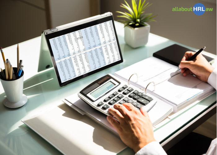 Calculating personnel costs for 2027 using a digital spreadsheet, calculator and budget planning documents.