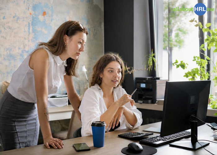 Two colleagues review a workflow on a laptop and question established habits that have become part of the company culture.
